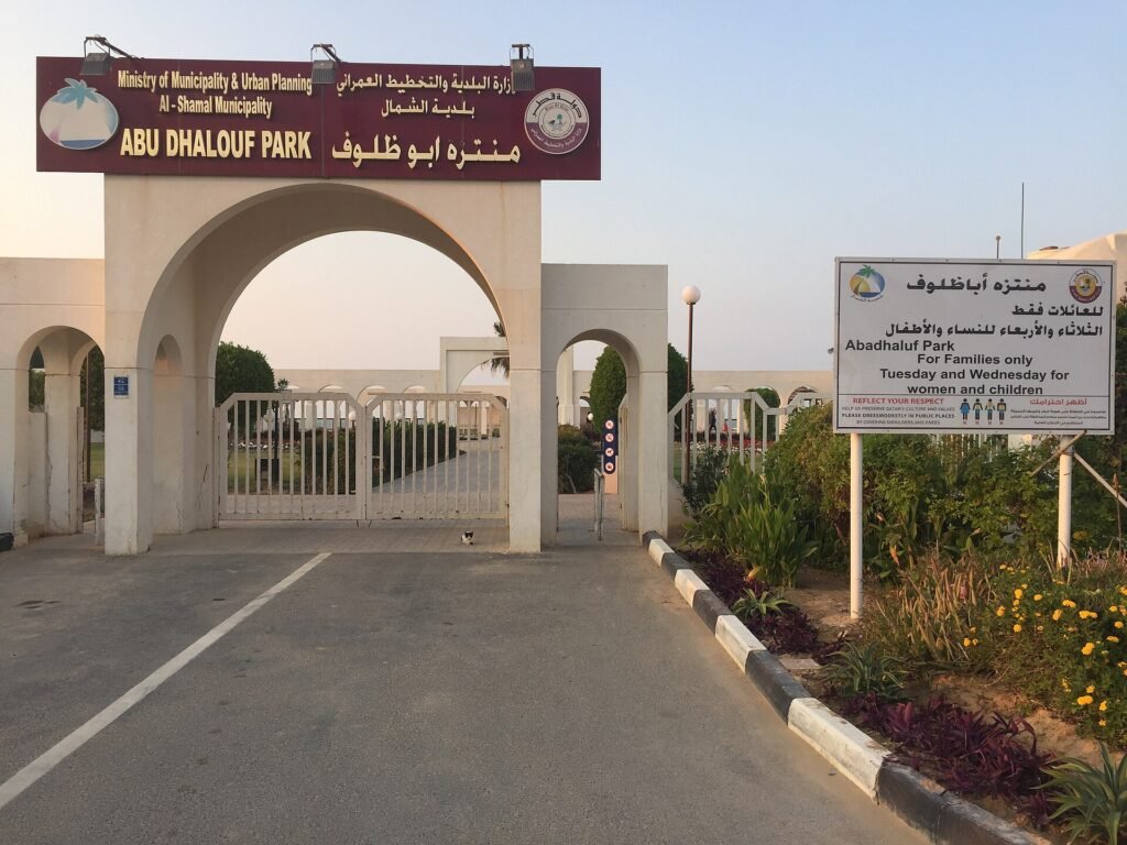 The arched white entrance gate of Abu Dhalouf Park in Al Shamal
