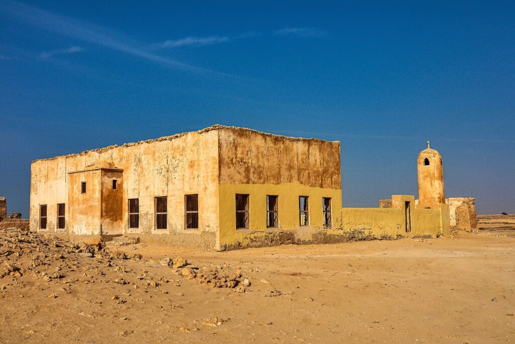 The mosque and minaret at Al Jumail abandoned village under a blue sky