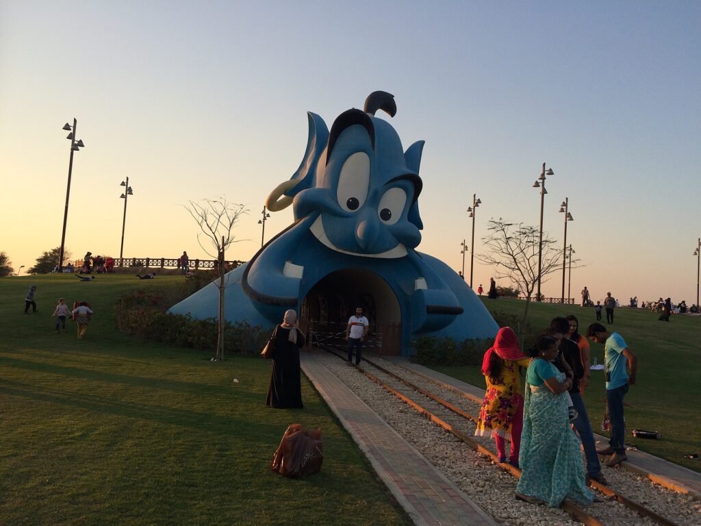 Large genie-themed sculpture with visitors at Al Khor Park at dusk