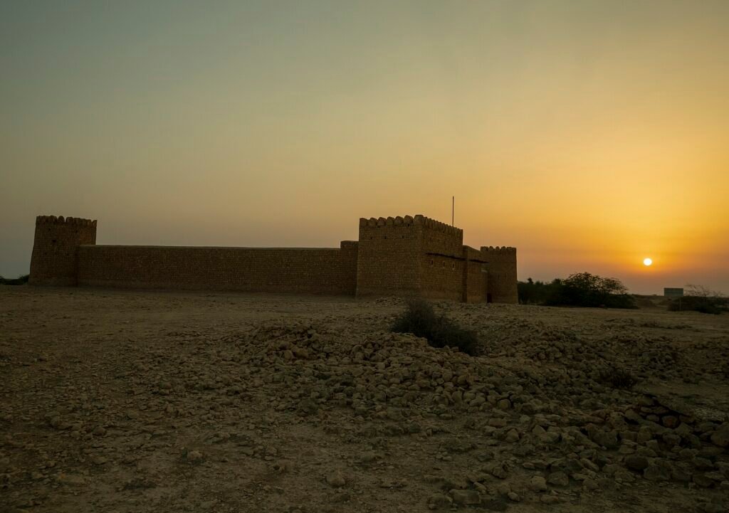 Al Thaqab Fort silhouetted against a golden evening sky