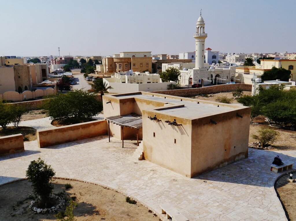 Restored plastered building beside the Barzan Towers with a mosque minaret behind