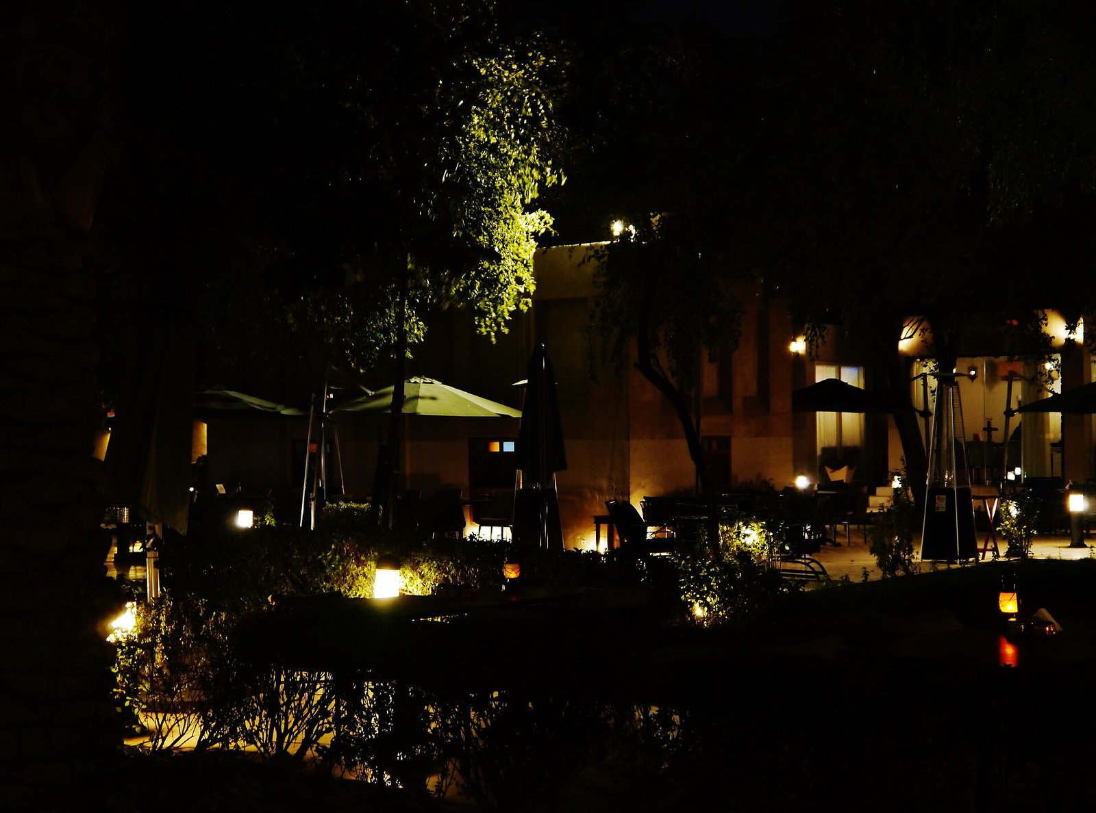 Bayt Sharq courtyard lit up at night among palm trees