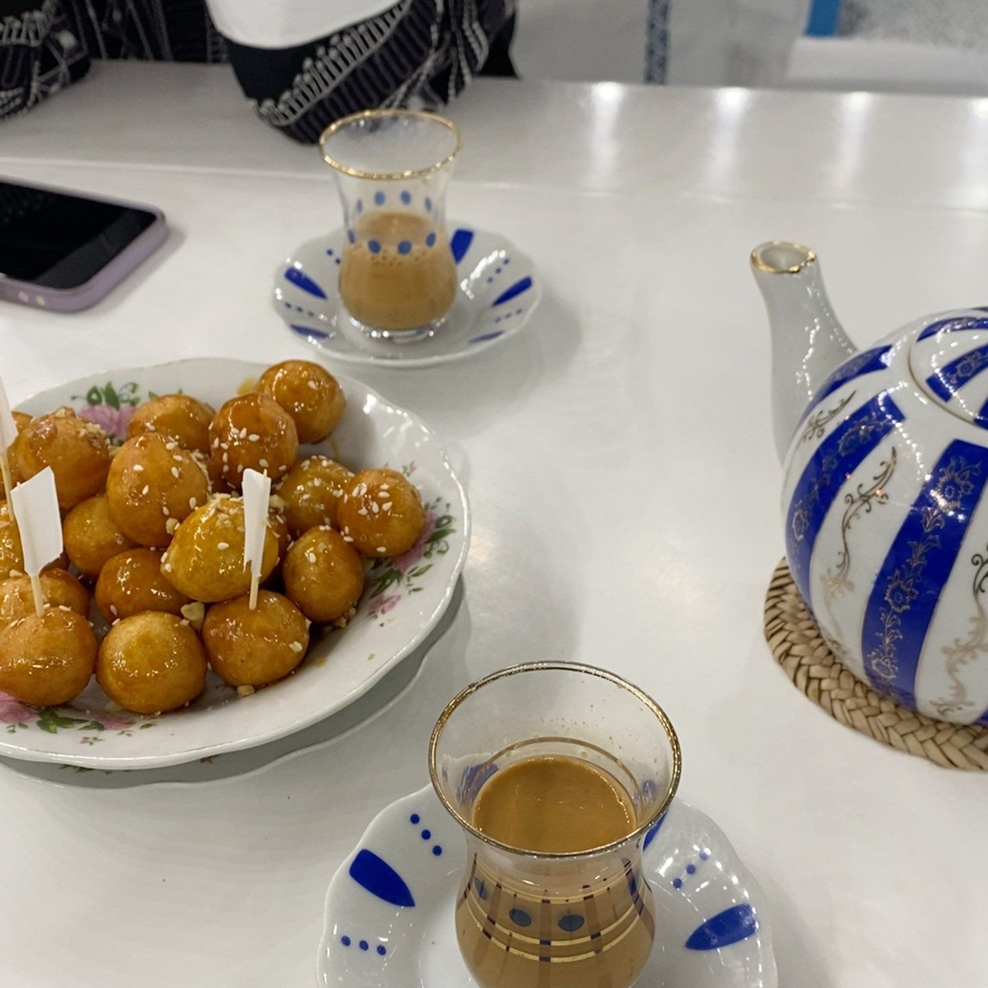 Glasses of karak tea served with luqaimat dumplings
