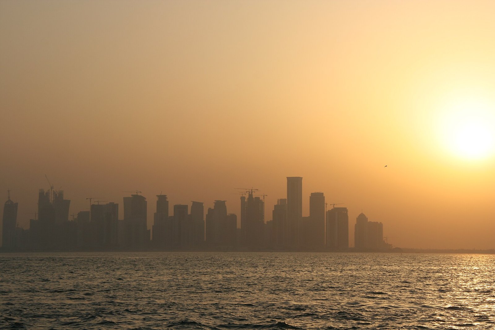 West Bay skyline in silhouette across Doha Bay at sunset