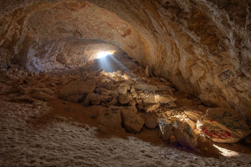 Sunlight streaming through the entrance into the rocky chamber of Dahl Al Misfir cave