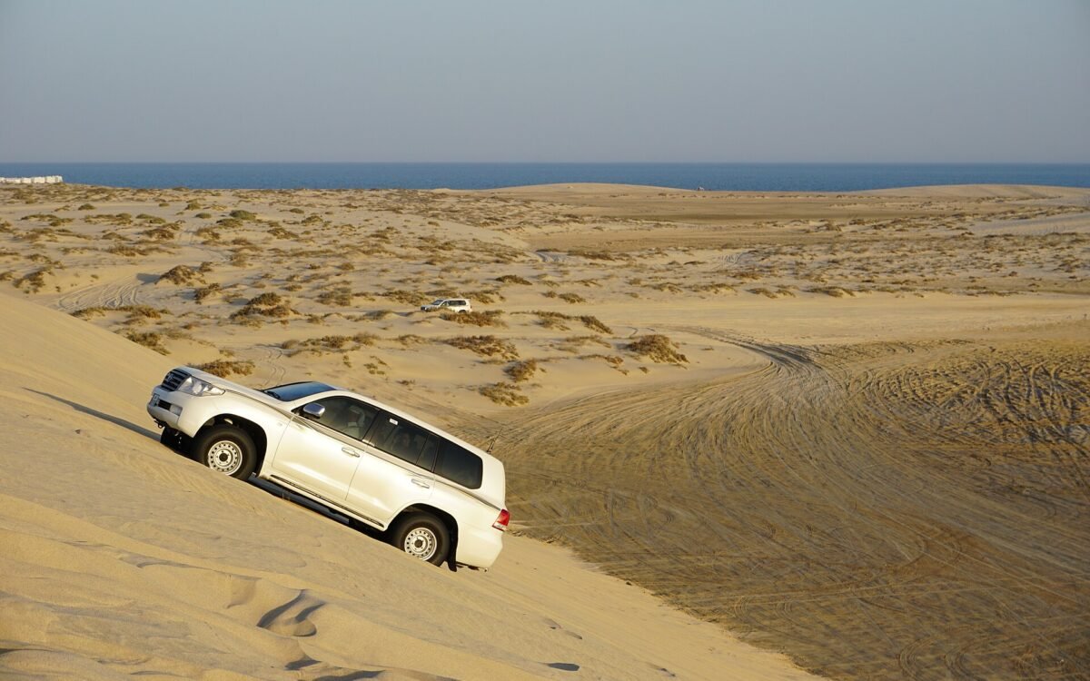 4x4 vehicle descending a sand dune above the sea on a desert safari in southern Qatar