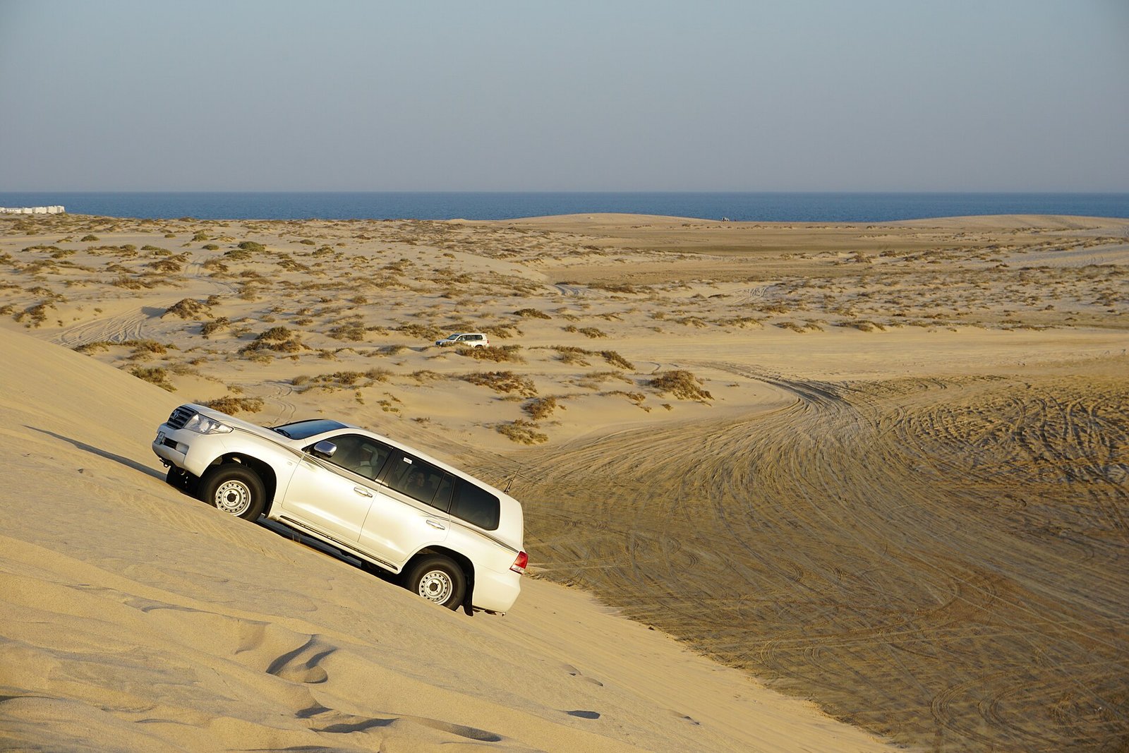 4x4 vehicle descending a sand dune above the sea on a desert safari in southern Qatar