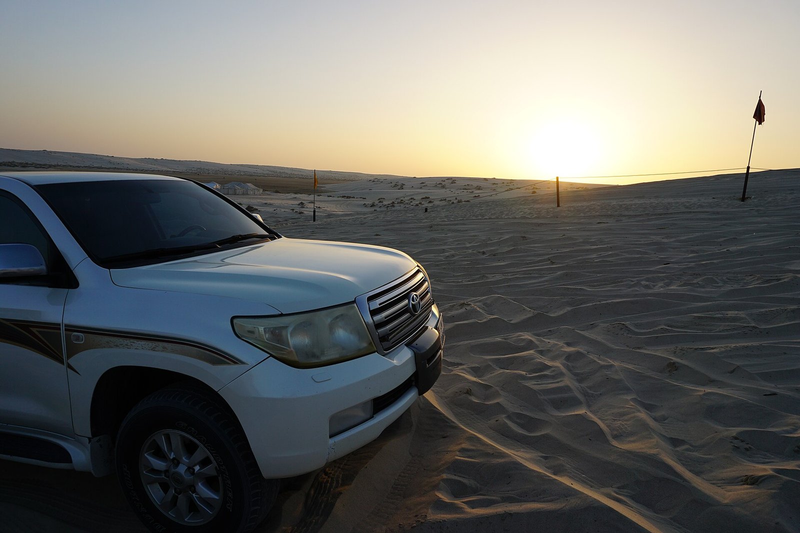 4x4 parked on the sand as the sun sets over the desert in Qatar