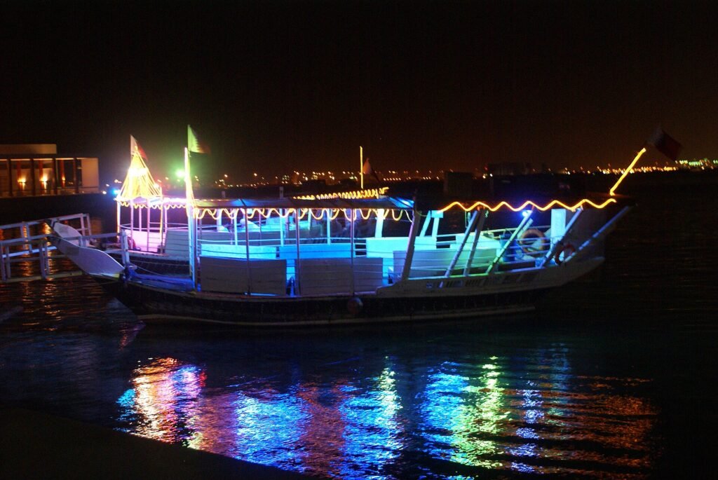 A dhow lit up with coloured lights at night on the Doha Corniche