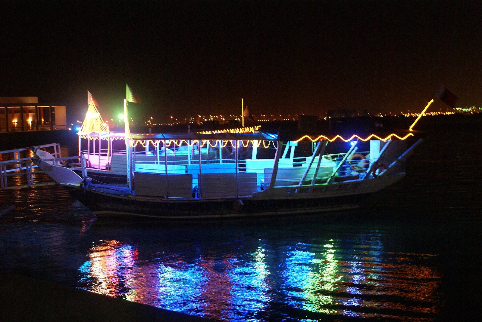 A dhow lit up with coloured lights at night on the Doha Corniche