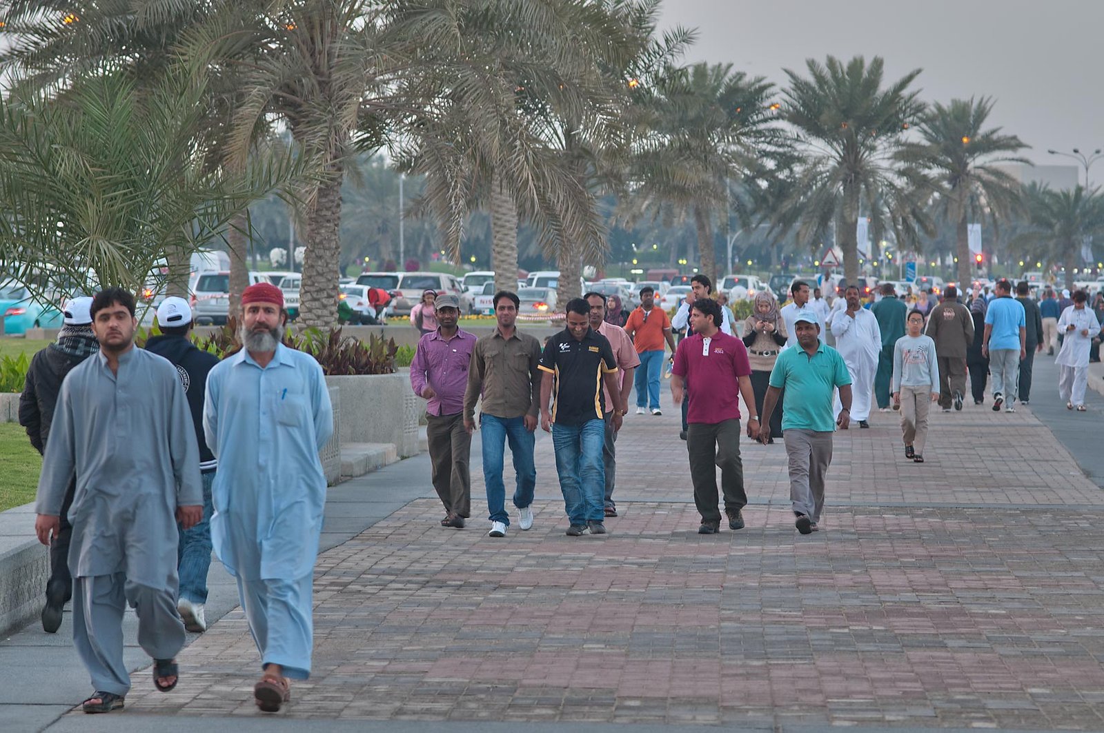 People walking along the palm-lined Doha Corniche promenade