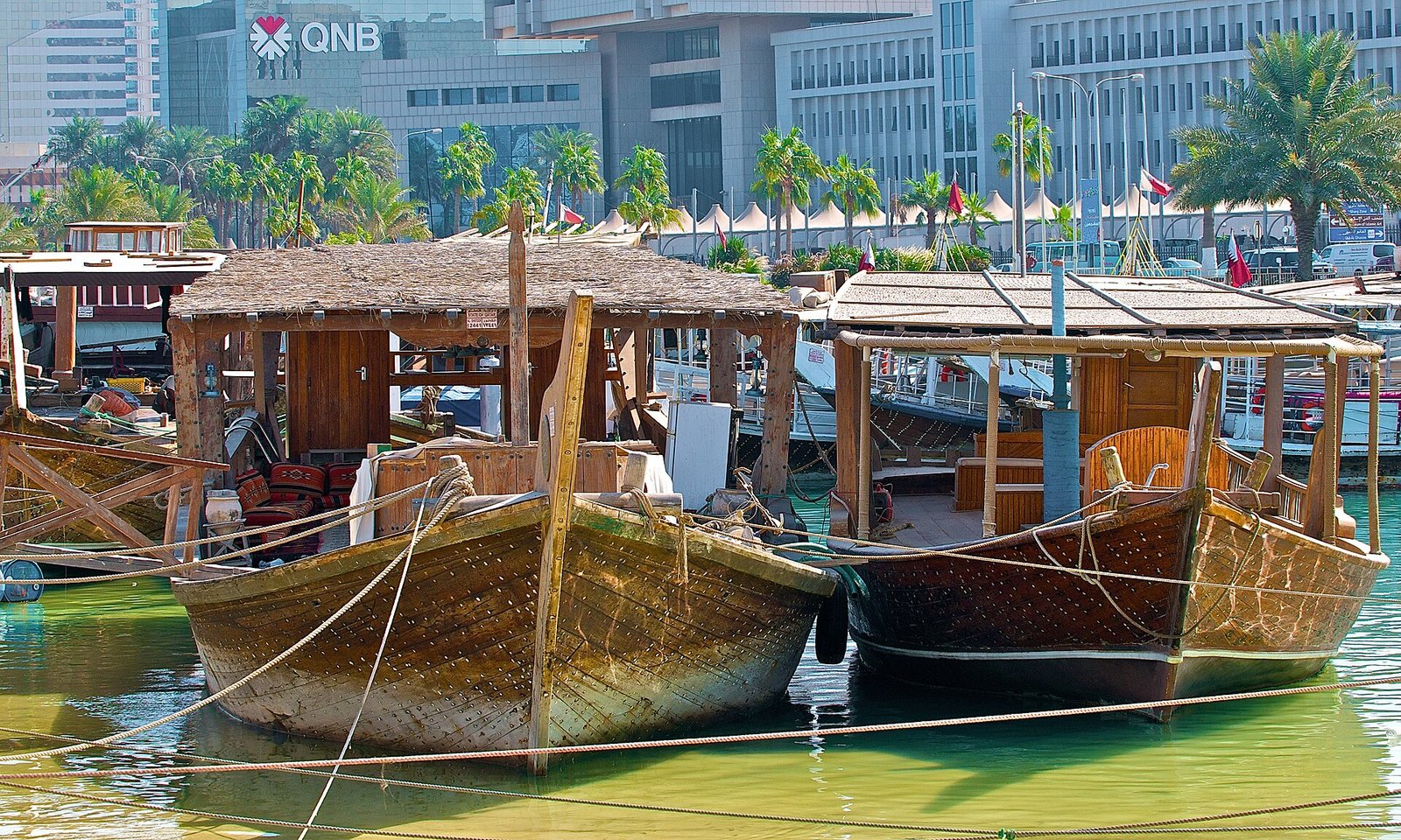 Traditional wooden dhows moored on the Doha Corniche with modern buildings behind