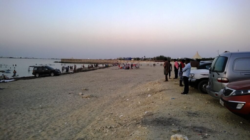 Cars parked along the sand at Dukhan Beach in the late afternoon