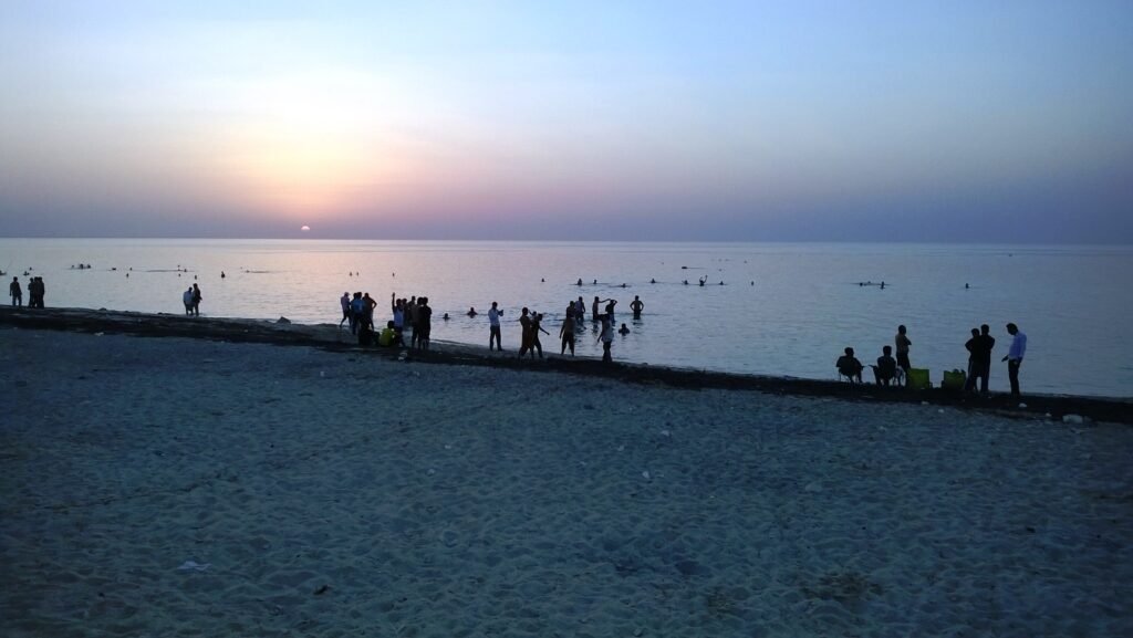 People at the water's edge watching the sunset at Dukhan Beach