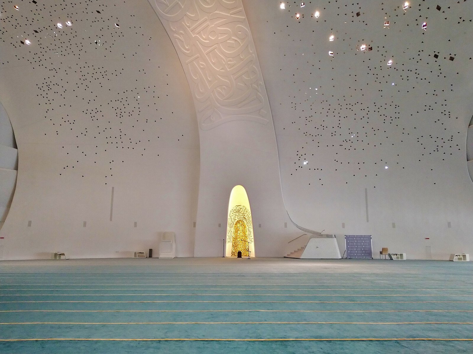 The column-free prayer hall of the Education City Mosque with its lit mihrab