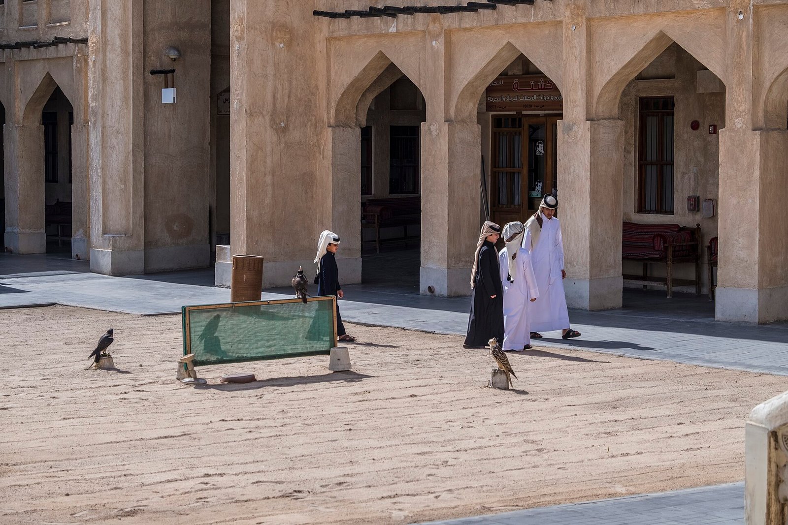 Arched shopfronts and falcons on a perch in the Falcon Souq courtyard