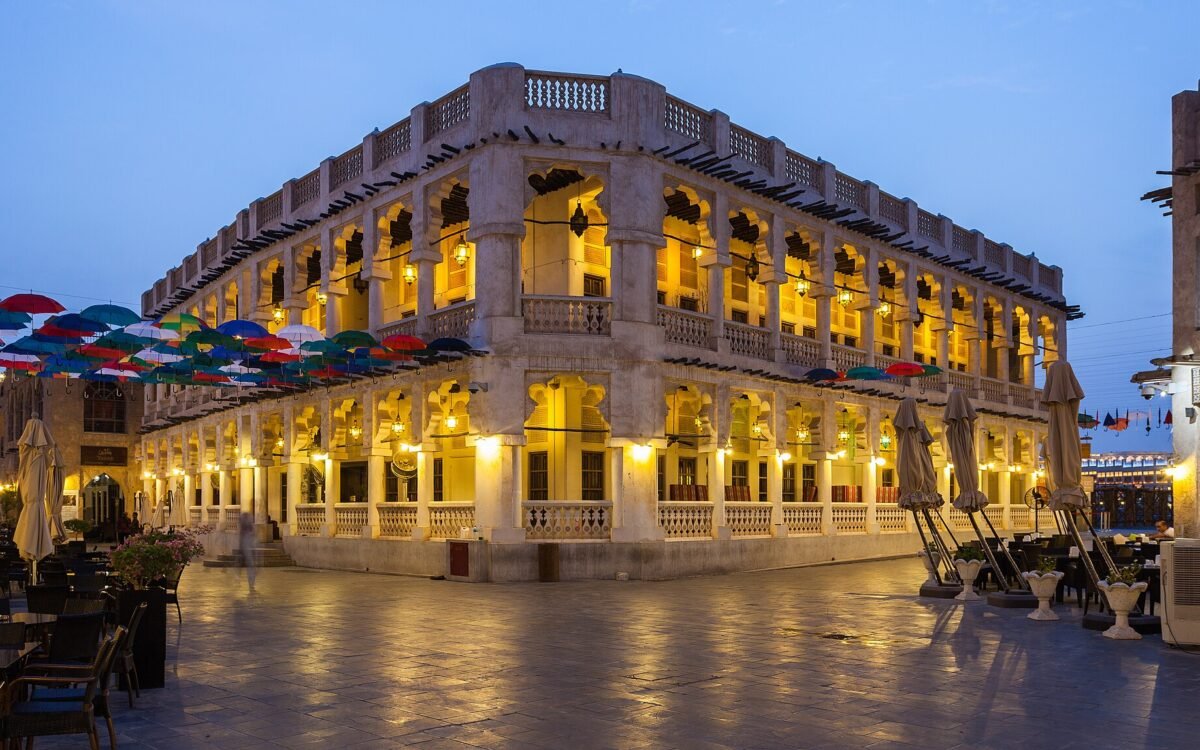 Souq Waqif in Doha lit up in the evening, with arcaded buildings and lanterns