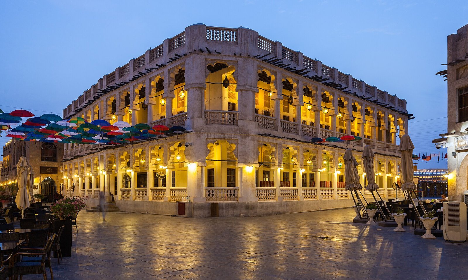 Souq Waqif in Doha lit up in the evening, with arcaded buildings and lanterns