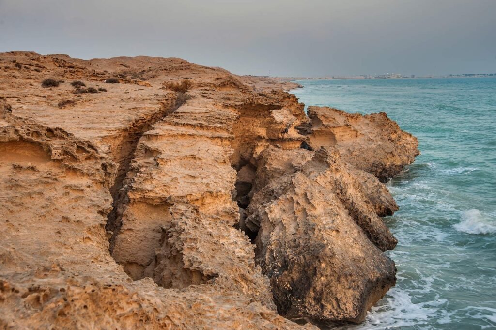 Weathered limestone cliffs of Jebel Fuwairit beside the sea