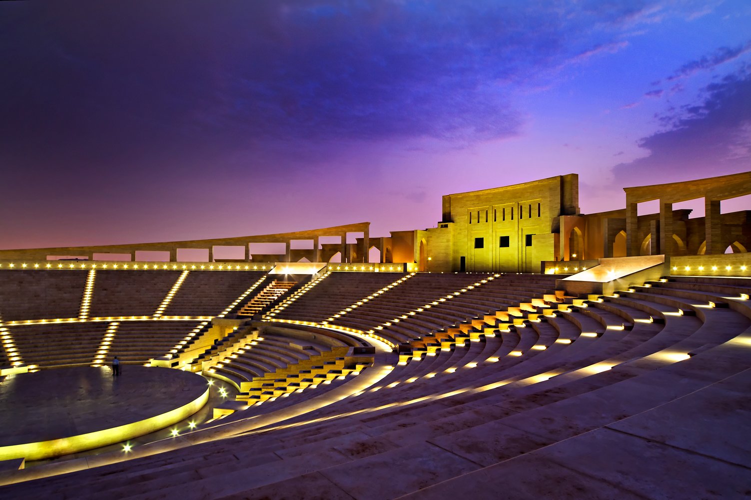 Katara Amphitheatre lit up at dusk, with tiered seating facing the stage