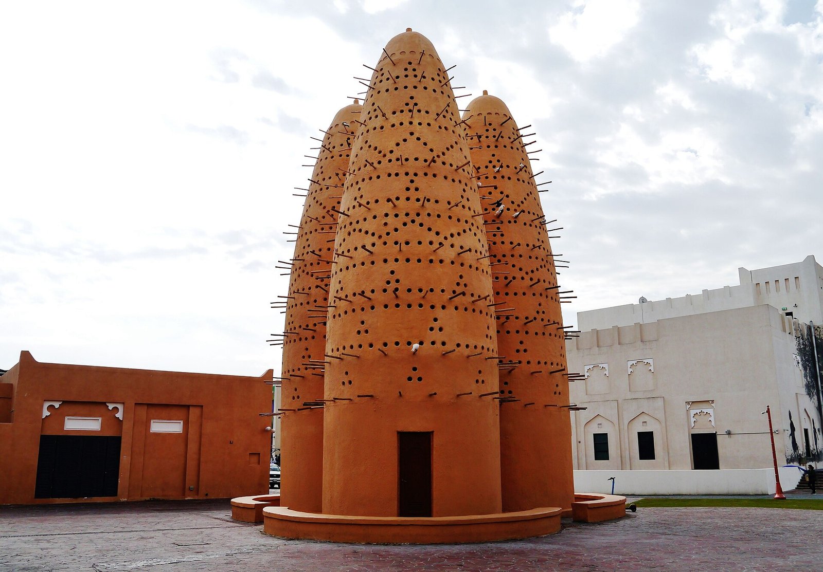 A cluster of tall clay pigeon towers studded with wooden perches at Katara