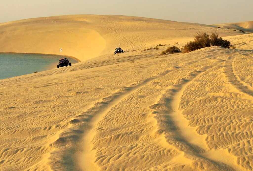 Tyre tracks and a 4x4 on the dunes above the lagoon at Khor Al Adaid