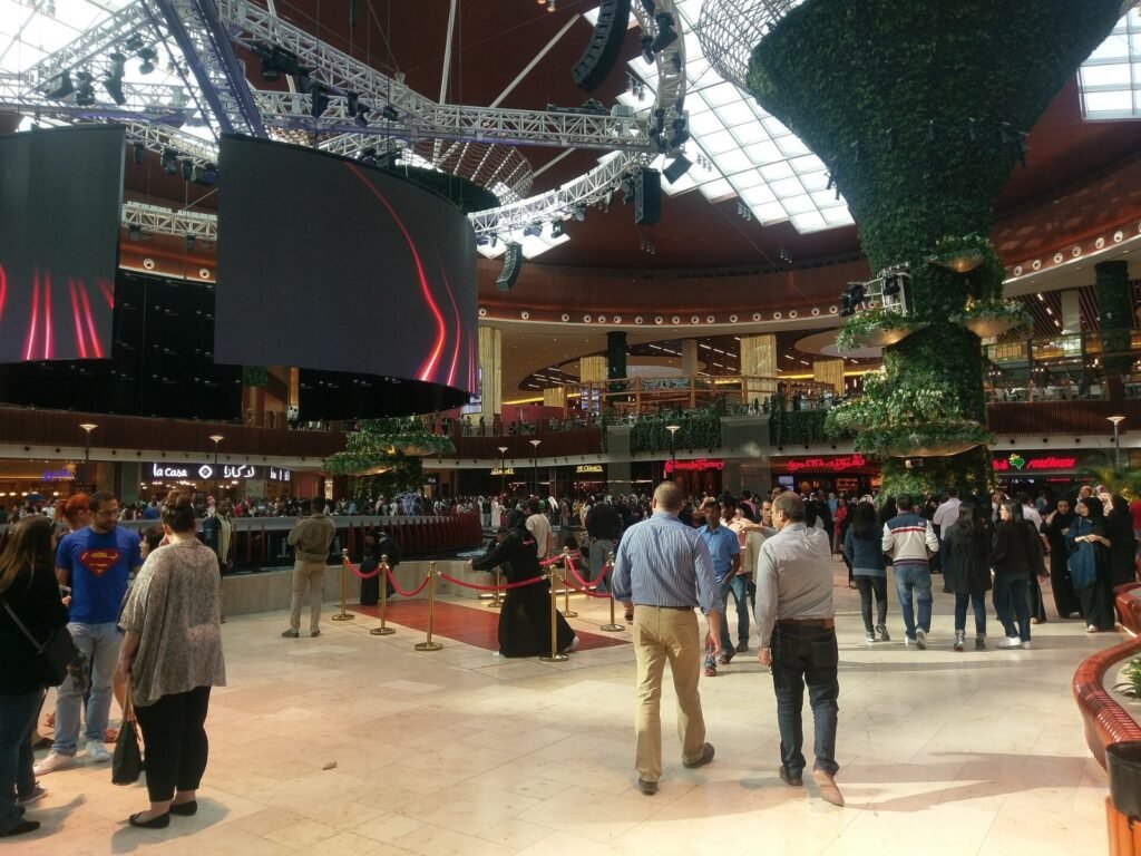 Shoppers on the ground floor of the Oasis at Mall of Qatar under the glass roof and big screens