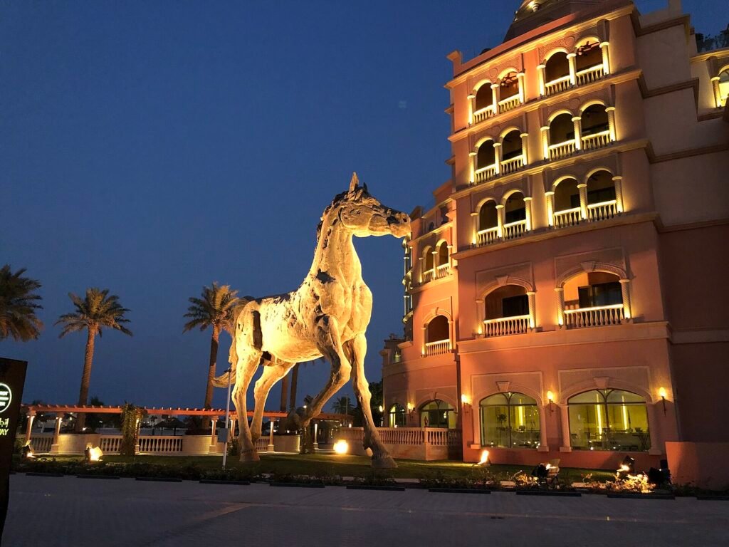 Illuminated horse sculpture in front of the Marsa Malaz Kempinski facade at night