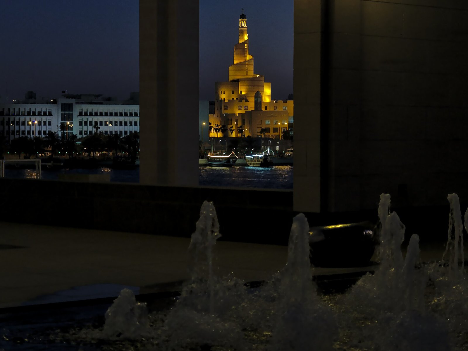 The Museum of Islamic Art atrium window at dusk, with the Fanar mosque minaret beyond