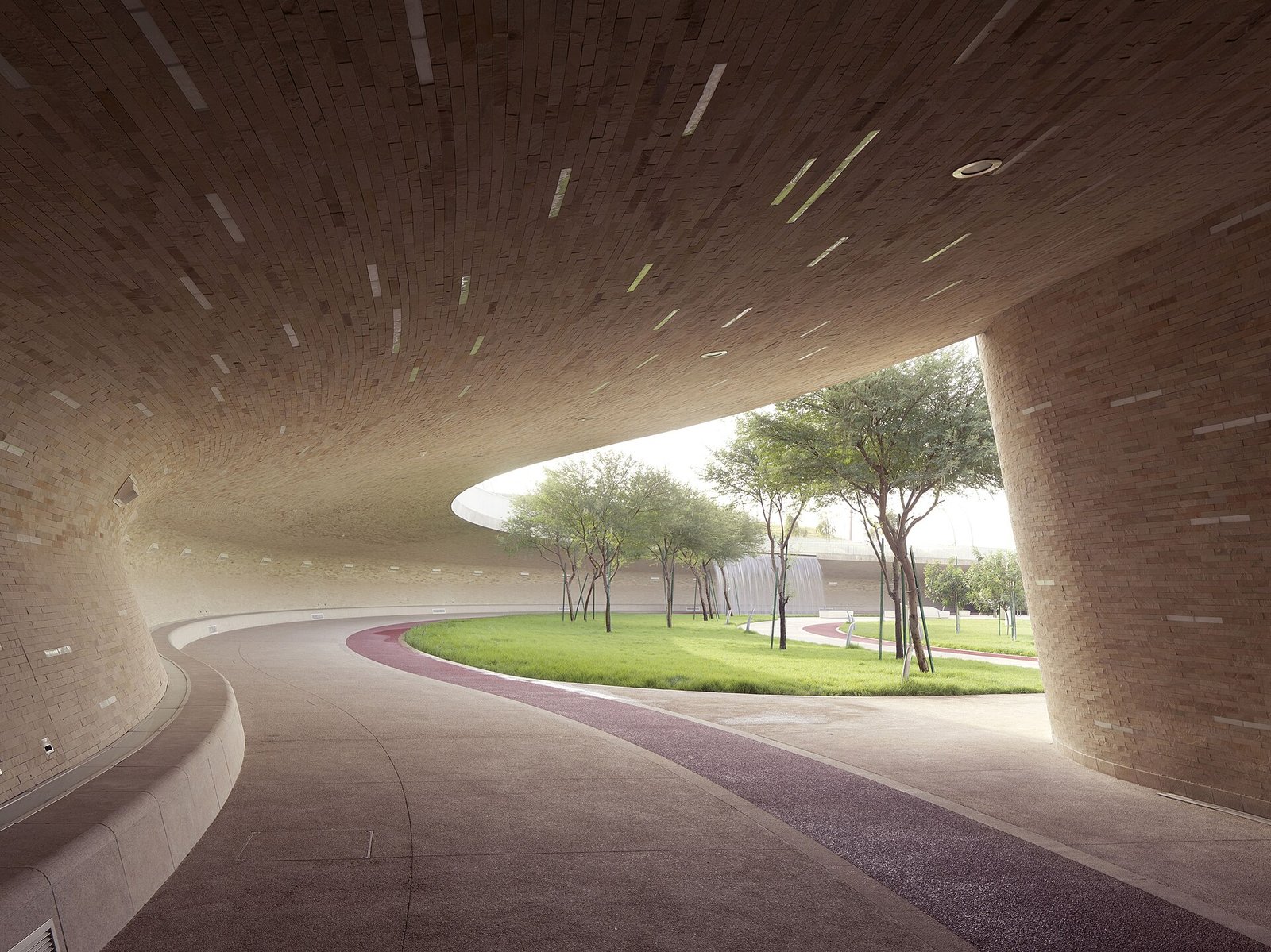 Curved shaded canopy over the running track at Oxygen Park with trees beyond