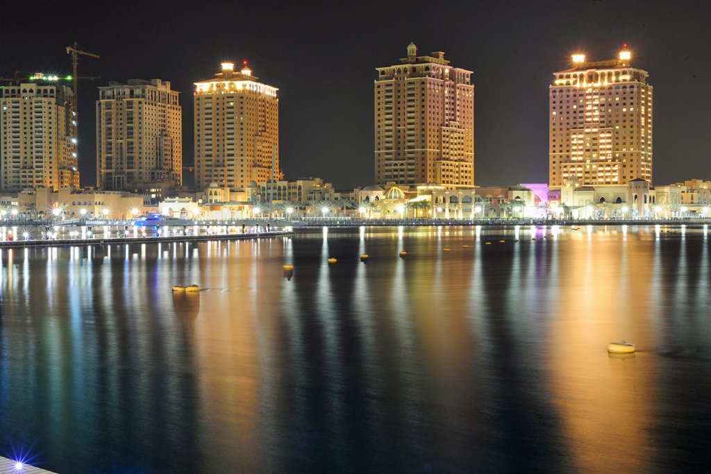 Porto Arabia towers lit up at night and reflected in the marina