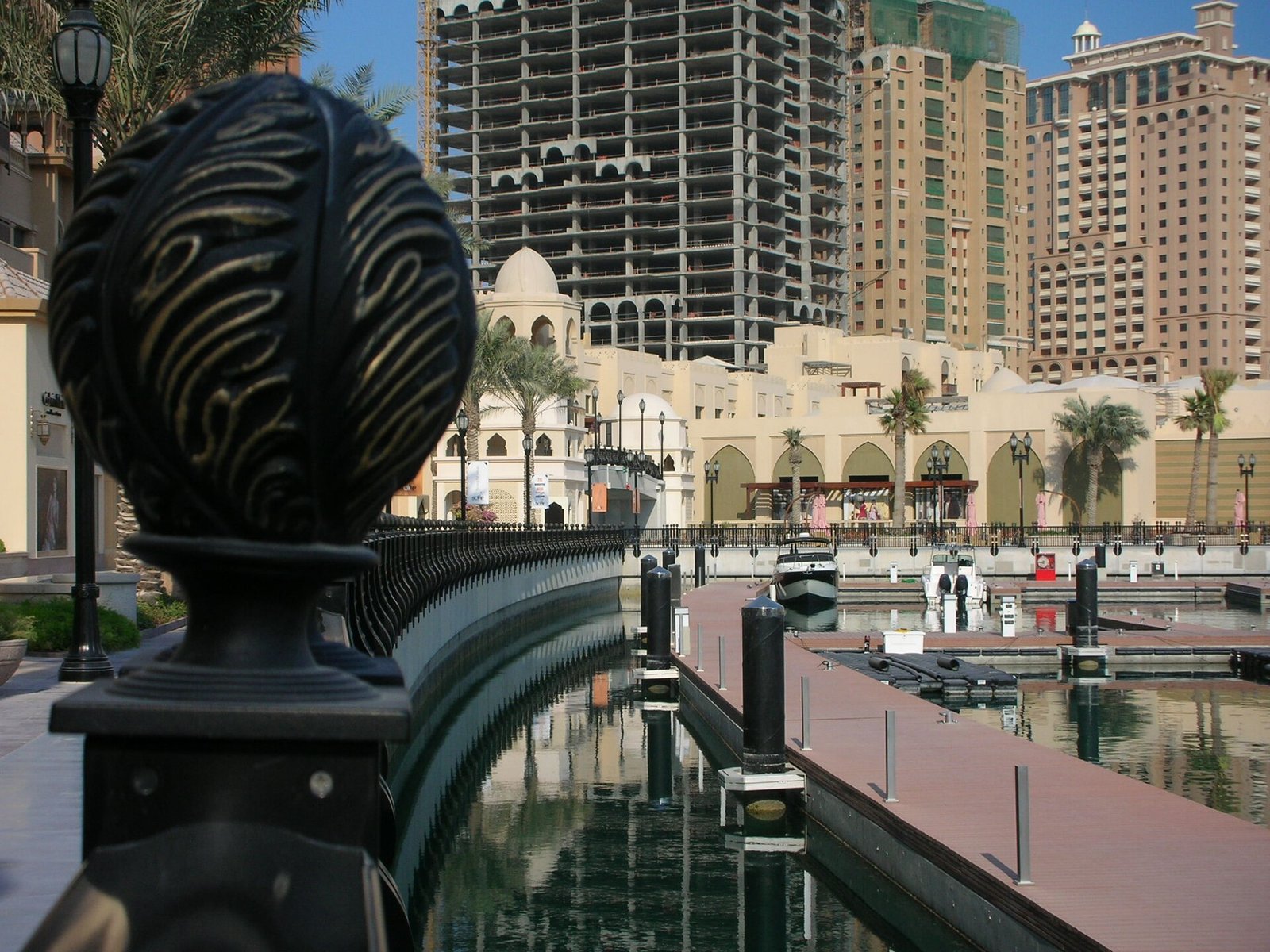 Marina-side walkway at Porto Arabia with Mediterranean-style buildings