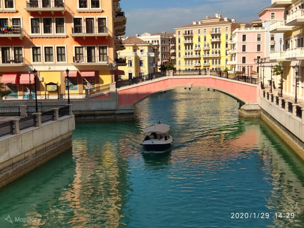 Small boat on a canal between colourful buildings at Qanat Quartier