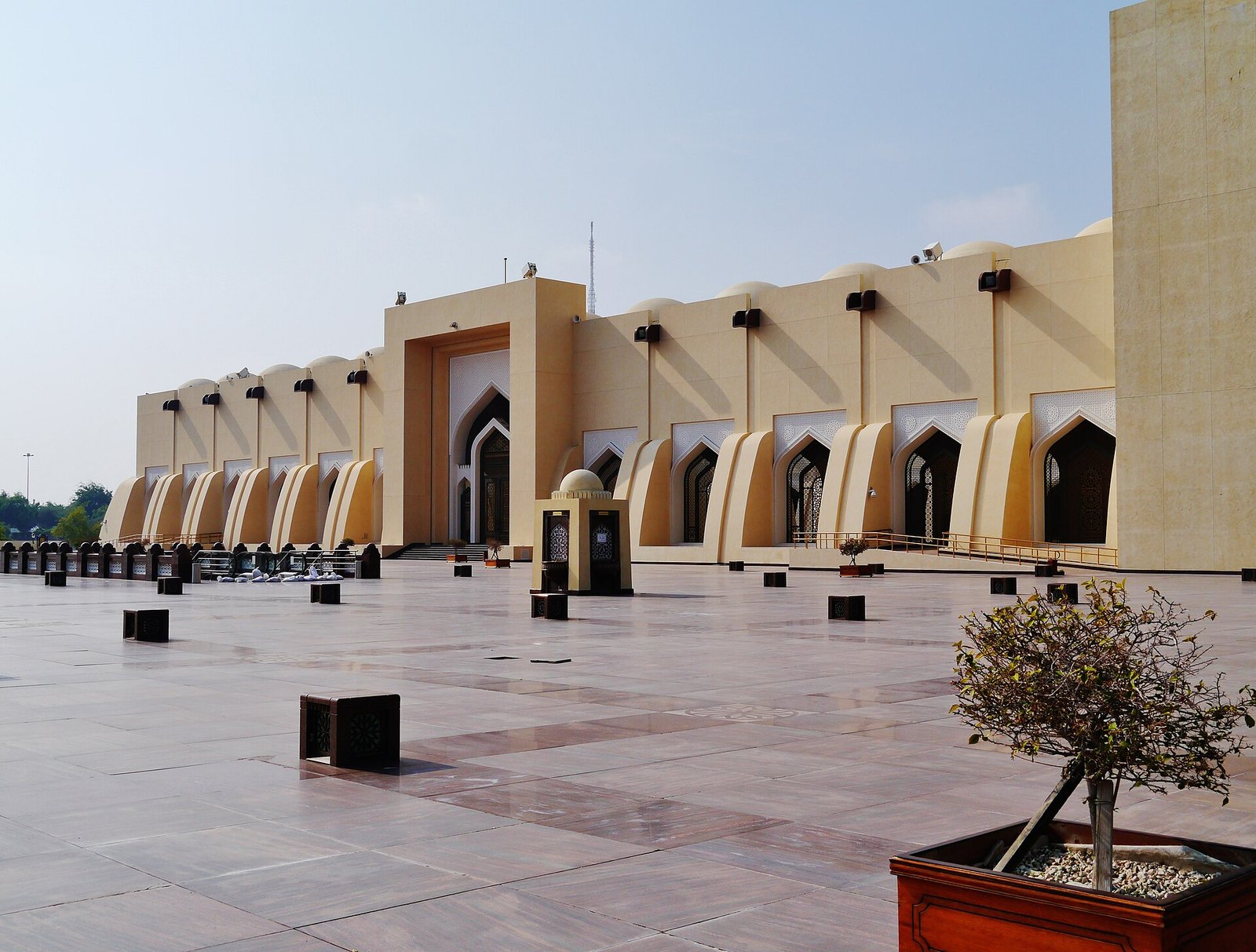 Sandstone arcade and the single square minaret of the State Grand Mosque in Doha seen from the marble courtyard