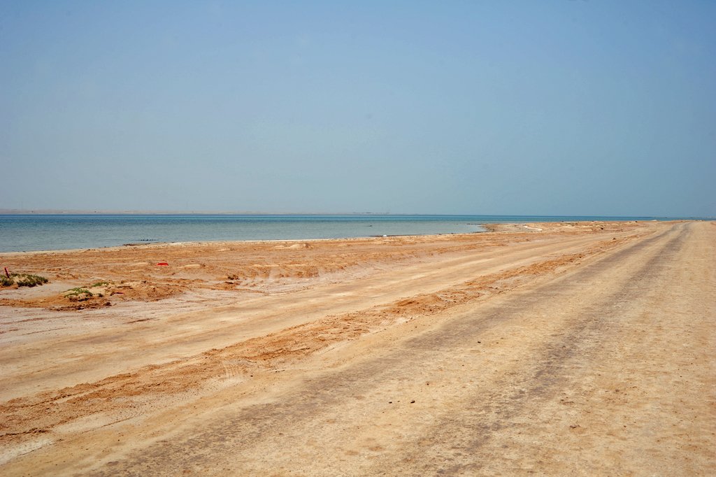 Empty sandy shoreline and calm sea on the Zekreet Peninsula coast
