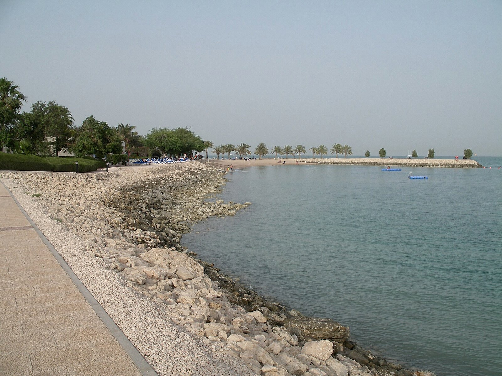 Rock-lined shoreline and promenade beside Sheraton Hotel Park in Doha