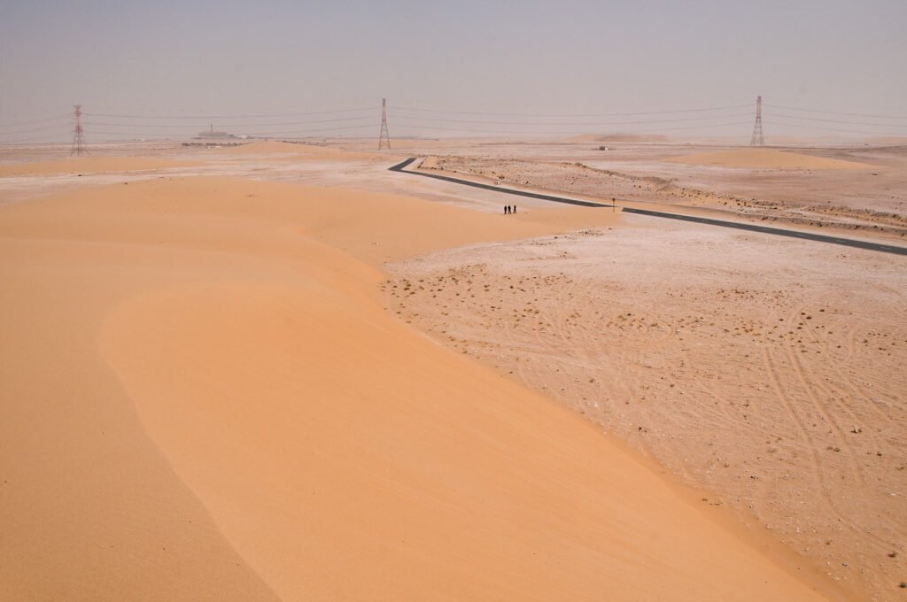 The smooth southern slope of the Singing Sand Dunes with flat desert beyond, Mesaieed