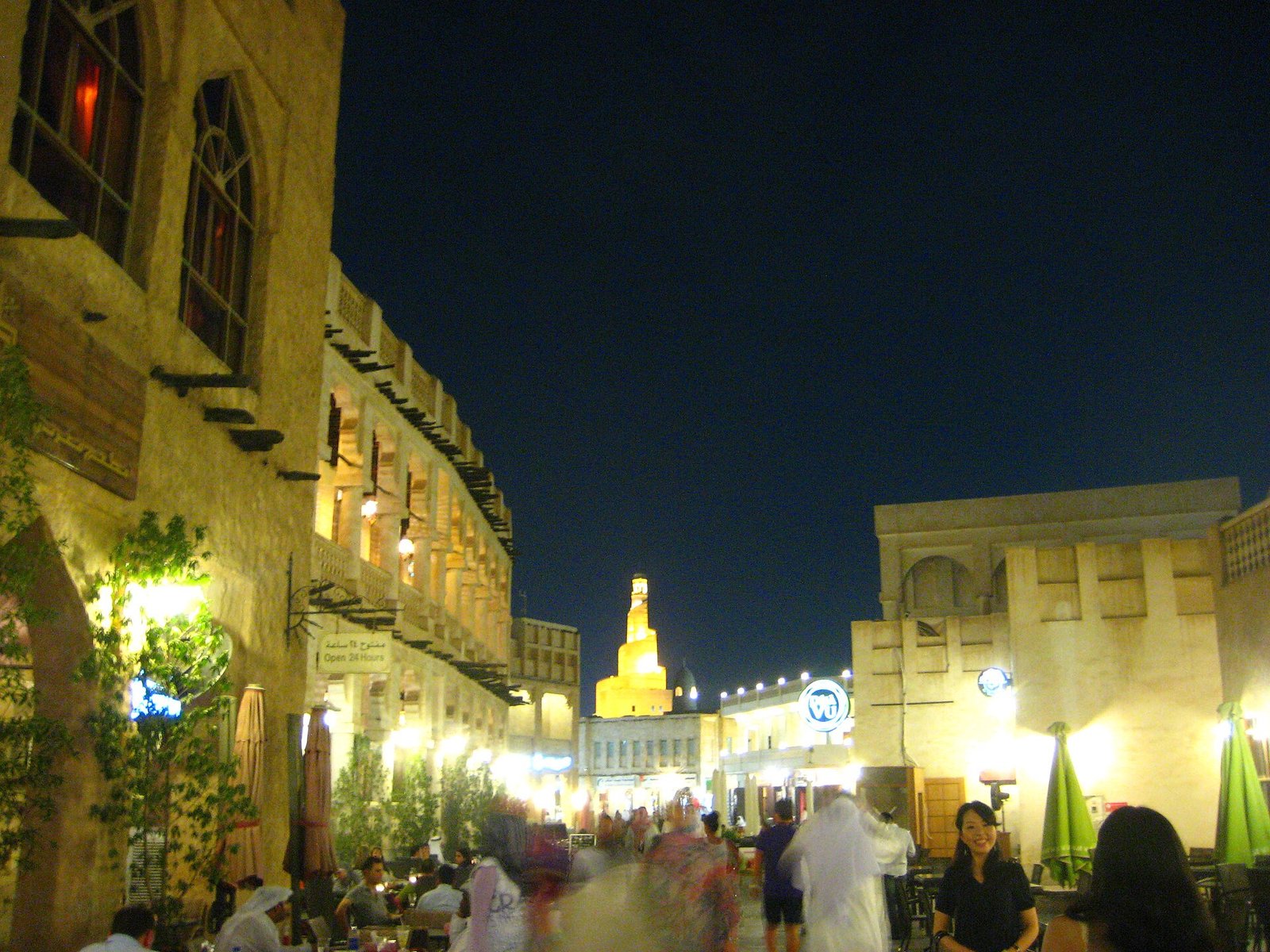 Souq Waqif lit up at night with the spiral minaret of the Islamic Cultural Centre behind