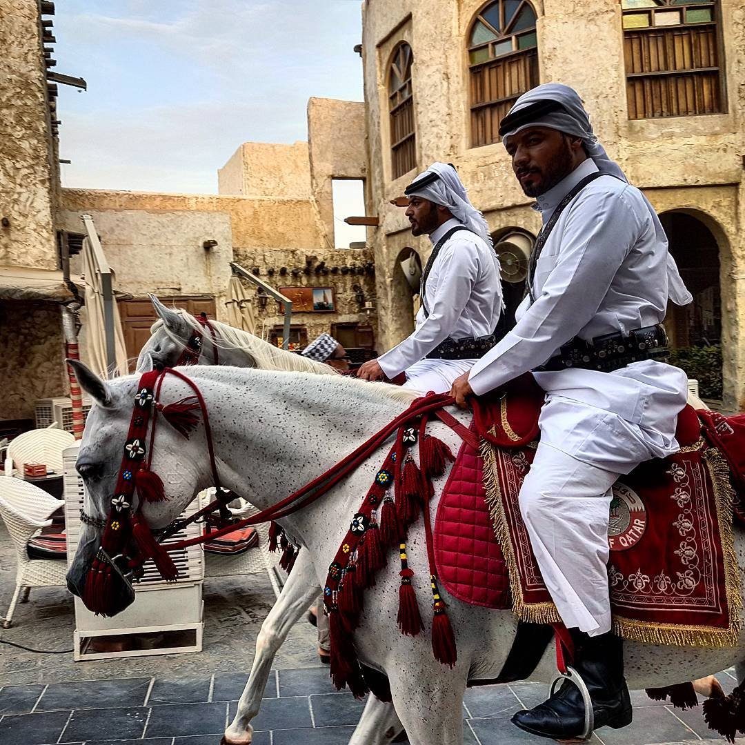 Heritage police riding white Arabian horses through Souq Waqif