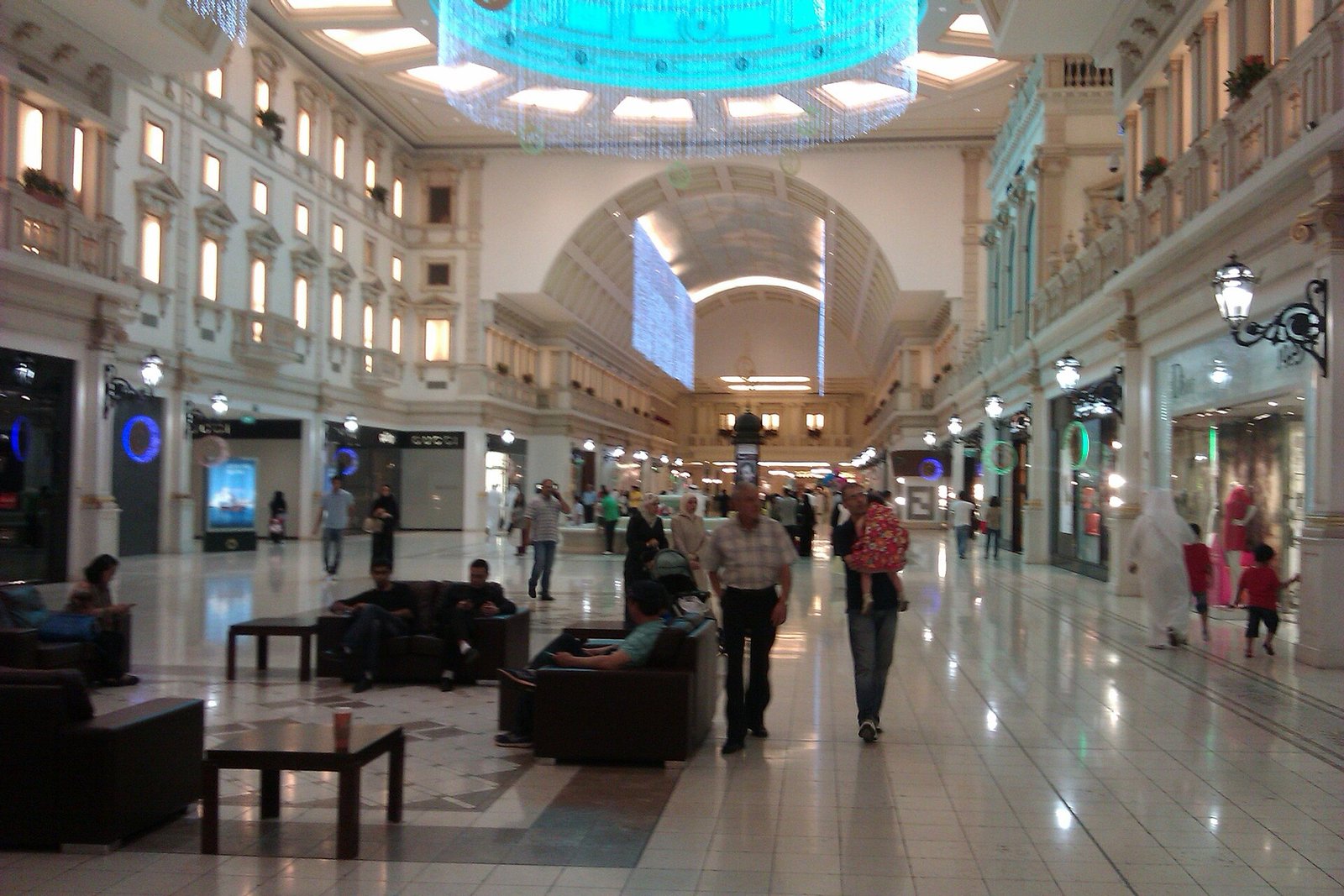Main shopping avenue inside Villaggio Mall with arched ceiling and café seating